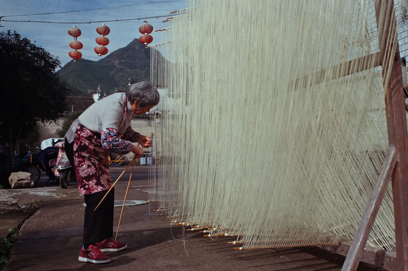 In a rare moment of winter sun, grandma Chen takes her long-life noodles out to dry.