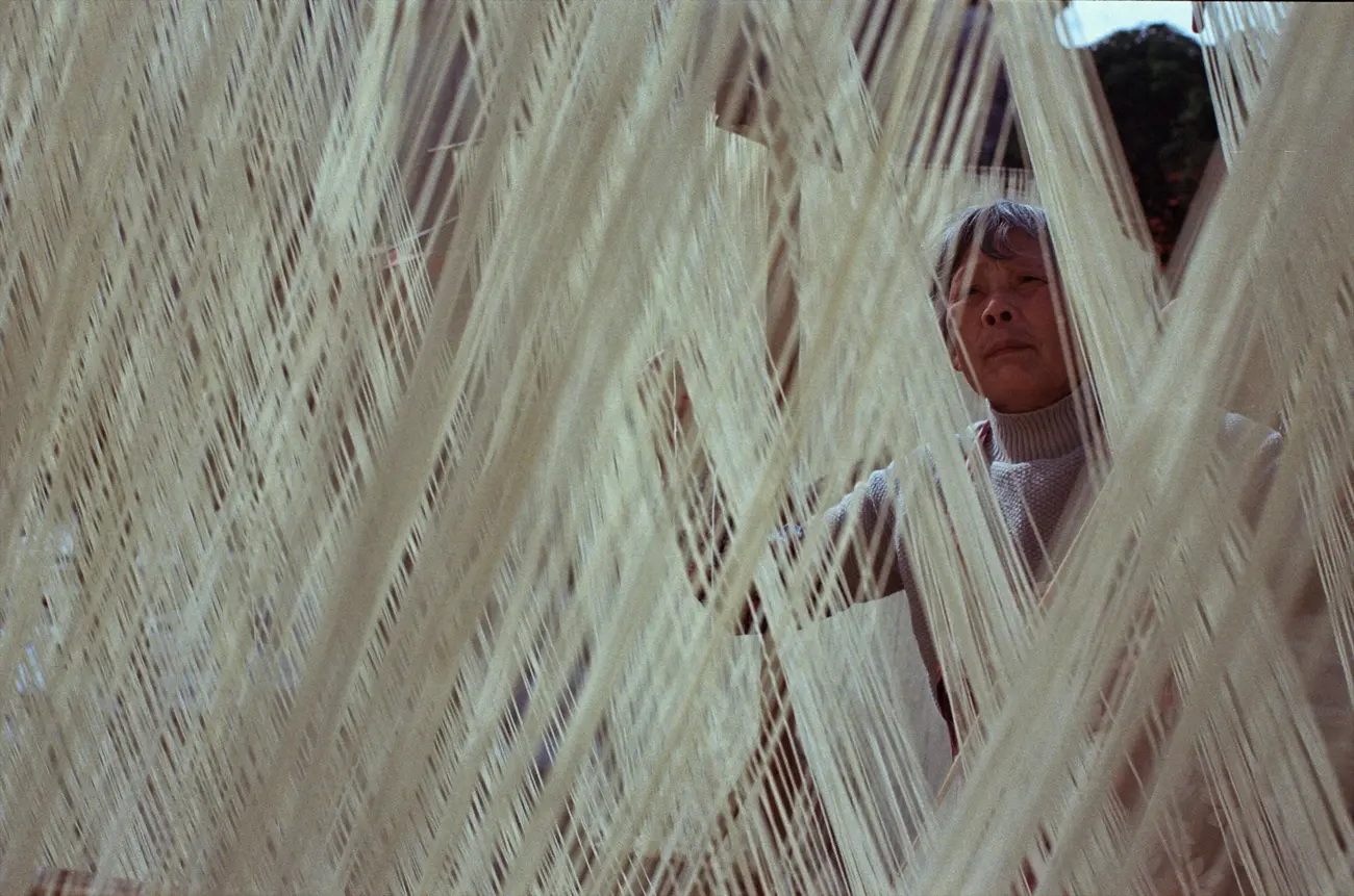 Chen-nainai takes extra care to separate the strands of her long-life noodles.