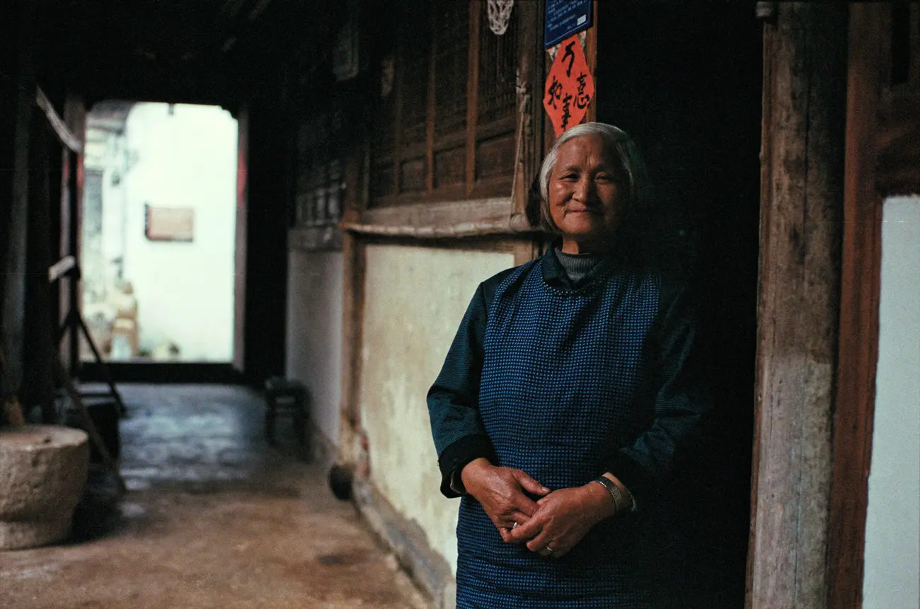 One of Chen-nainai's neighbours watches the film crew curiously from the front door of her house.